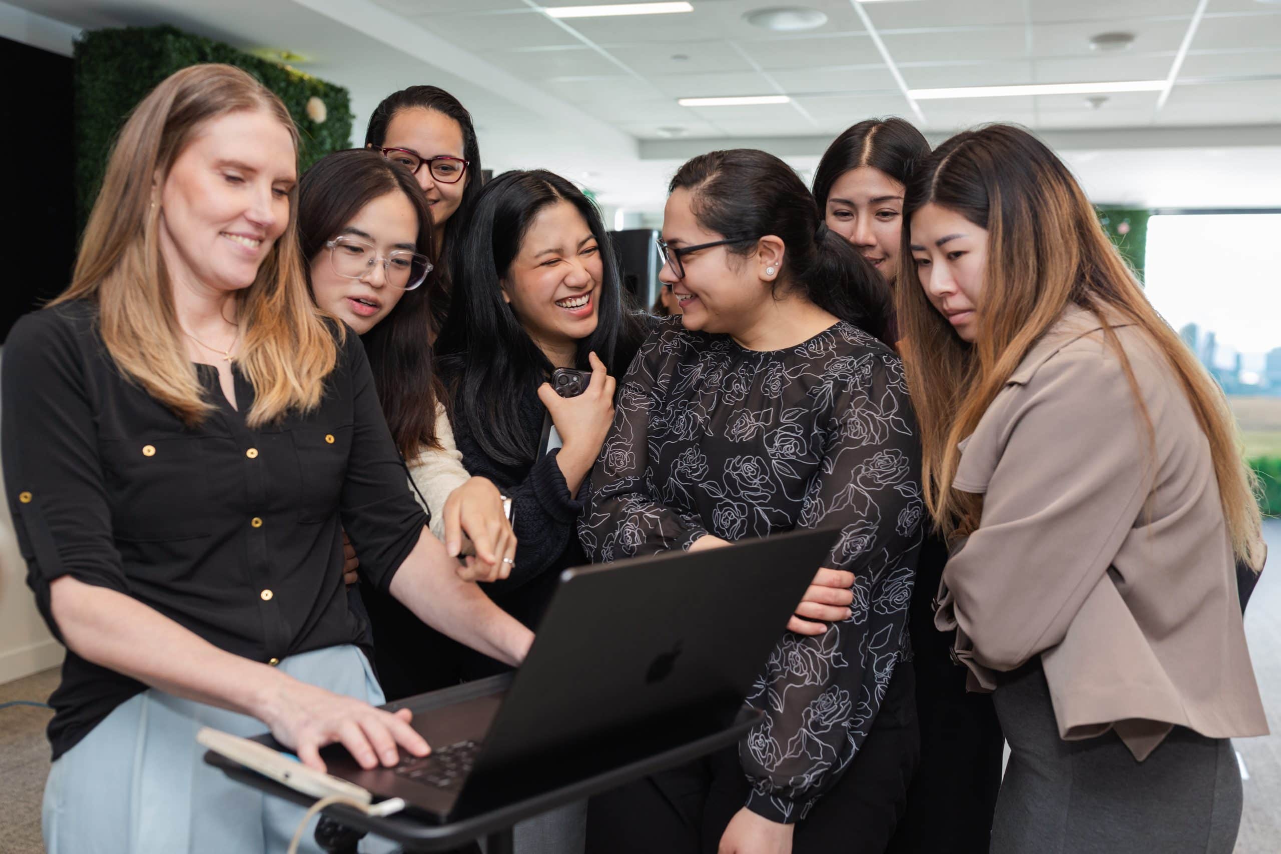 Diverse group of women engaging with a laptop during QuadReal’s IWD celebration series.